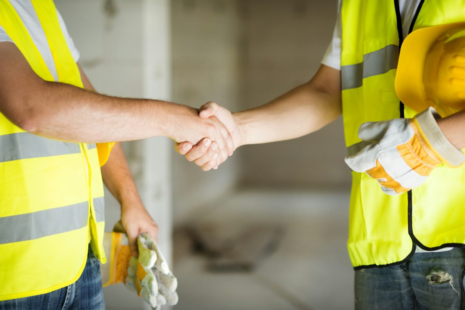 Client shaking hands with a contractor on a completed construction site, symbolizing a successful project