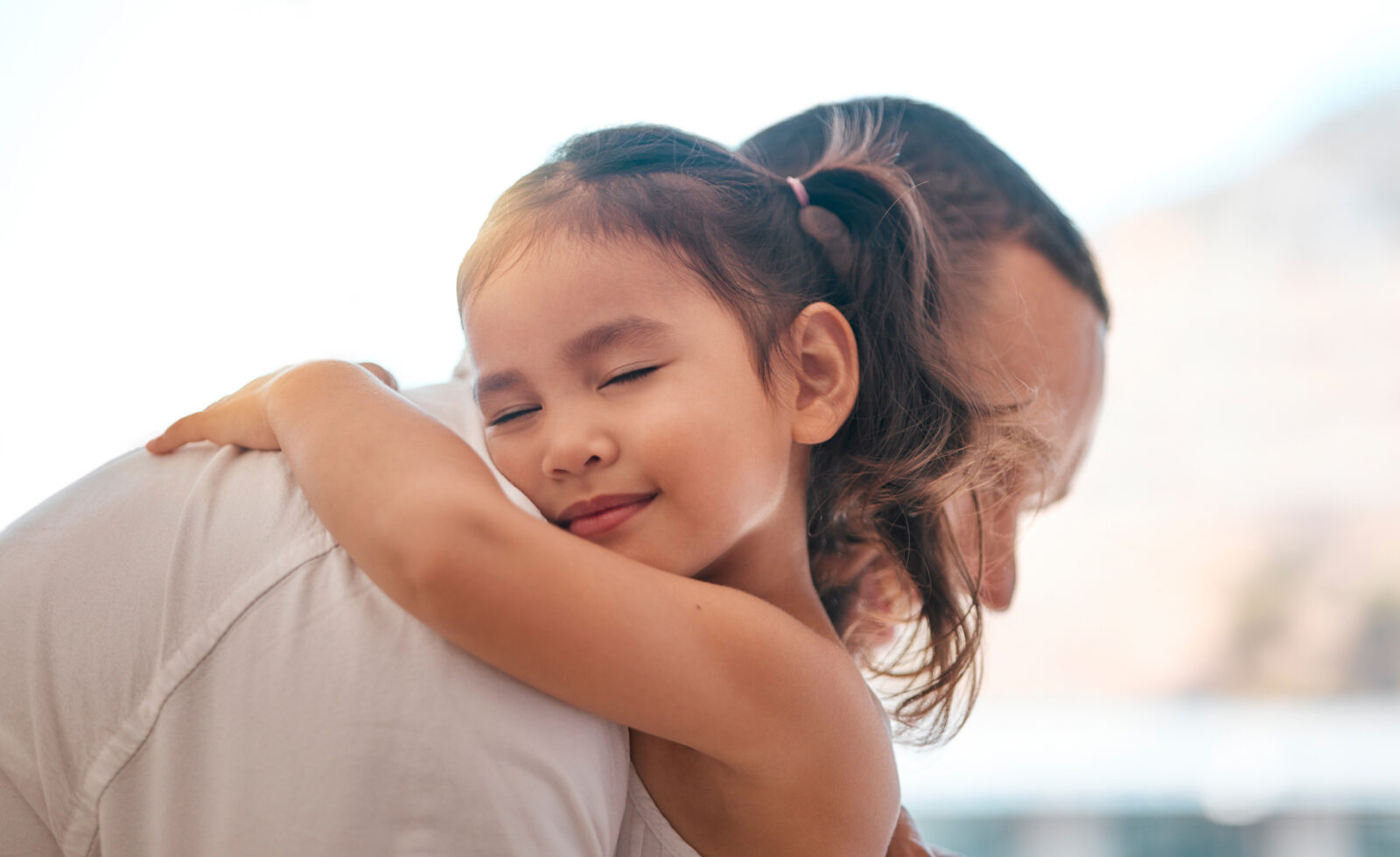A young girl with a joyful expression embraces her adoptive parent, symbolizing love, security, and the emotional bond created through adoption.